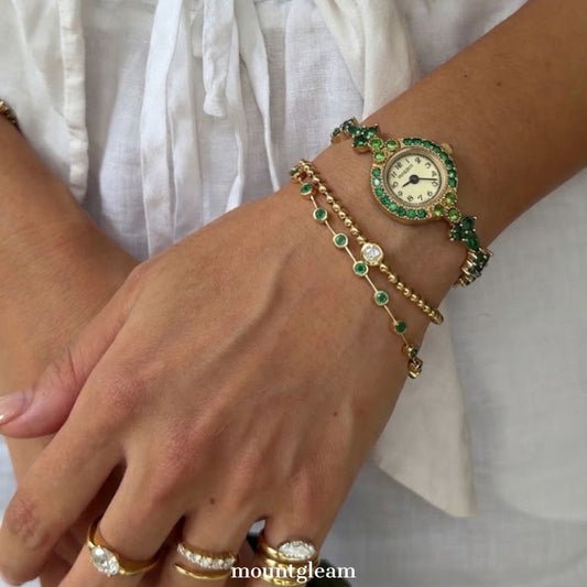 Emerald Luxe: Gold Round Dial Watch with Green Gemstone Bezel & Green Accent Bracelet