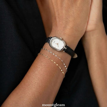 Moderne Eleganz: Uhr mit weißem, länglichem, ovalem Zifferblatt, silberner Lünette und schwarzem Mikrofaserlederarmband