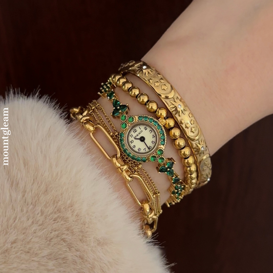 Emerald Luxe: Gold Round Dial Watch with Green Gemstone Bezel & Green Accent Bracelet