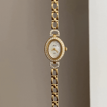 Luminous Chic Elegant: White Mother-of-Pearl Oval Dial Watch with Gold Diamond Bezel & Stainless Steel Bracelet.