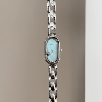Elegante Anmut: Blaue Uhr mit länglichem ovalem Zifferblatt, silberner Lünette und perlenbesetztem Kettenarmband